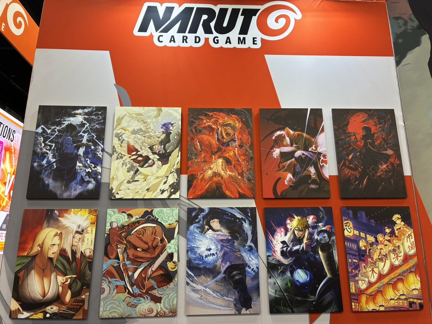 Ten Naruto Card Game art panels on the Bandai Gen Con booth wall, including Sasuke, Naruto in Nine-Tails cloak, Itachi, Hinata, Minato and Gamabunta